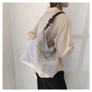 Detail of silk tote bag featuring floral prints and unique wood bead metal chain straps