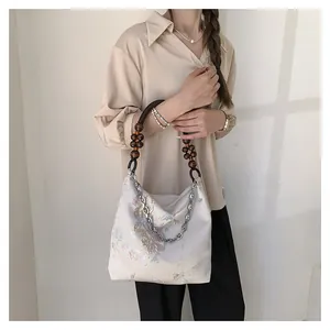 Detail of beige silk tote with floral embroidery and wooden bead chain strap