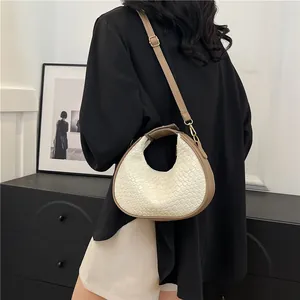 Detail of white woven hobo bag with brown leather straps and gold metal hardware