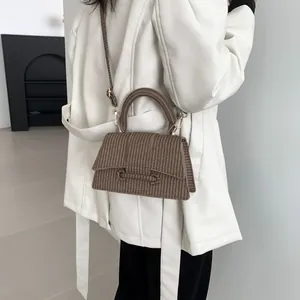 Détail du sac à main marron tissé montrant le rabat trapèze et la poignée en cuir