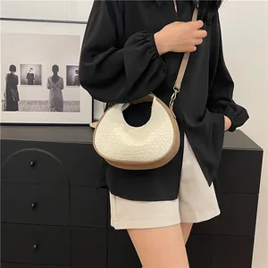 Detail of crescent shoulder bag with white crocodile pattern and brown leather straps