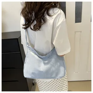 Rear view of a light blue large capacity hobo shoulder bag with vertical stitching