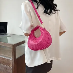 Macro shot of fuchsia woven crescent bag with gold-tone hardware on a model