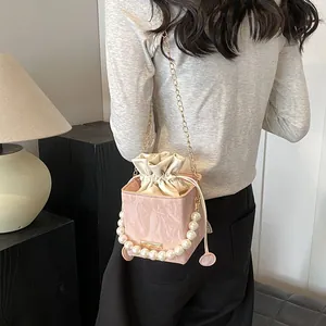 Pink marble pattern bucket bag with pearl handle and gold chain strap on model