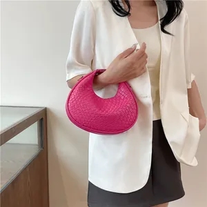 Detail of fuchsia woven crescent bag with leather texture and zip closure for women