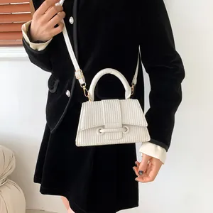 Sac à main trapèze blanc à texture verticale et détails dorés sur tenue en velours noir