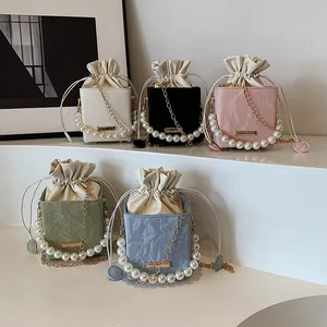 Mini textured leather drawstring bucket bag with pearl handle and metal chain strap
