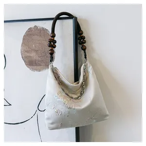 Detail of floral butterfly embroidery on canvas bag with beaded wooden strap and silver chain