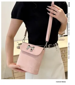 Primer plano de bolso rosa tipo cubo con detalle de lazo metálico plateado elegante