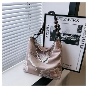 Detail of silk hobo bag featuring floral embroidery with wood beads and silver chain strap