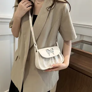 Detailansicht der weißen Plissee-Tasche mit silberner Schmetterlingsschnalle und Schultergurt