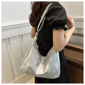 Silver large hobo shoulder bag with textured pearl finish worn by model in casual style