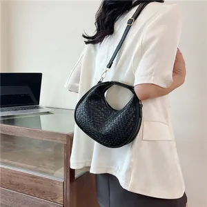 Detailed view of black woven crescent bag featuring intricate checkerboard faux leather texture