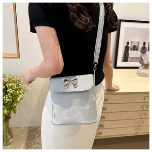 Detalle de bolso bandolera gris azulado con hebilla elegante de lazo de metal plateado