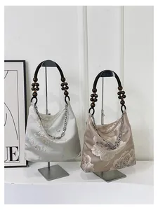 Detail of silk tote bags with floral embroidery, wooden bead handles and chain straps