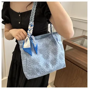 Detailed close-up of light blue floral embroidered tote bag with a decorative silk scarf