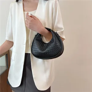Detail of black woven leather crescent bag featuring a metallic gold zipper and sleek texture