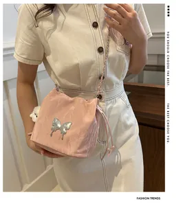Pink drawstring bucket bag with silver butterfly charm and chain strap on person