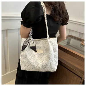 Detail of floral jacquard texture on beige tote bag with woven strap and silk scarf
