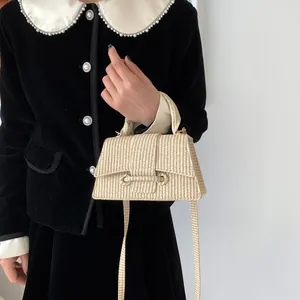 Détail d'un sac à main tissé crème avec rabat texturé et bandoulière sur le mannequin