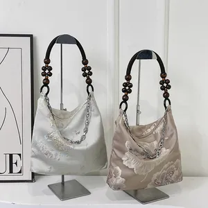 Elegant Chinese silk tote bag with floral patterns and wooden bead handles in soft lighting