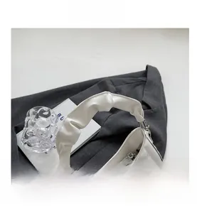 Close-up of pleated handle and quilted rhombic pattern on white stylish handbag