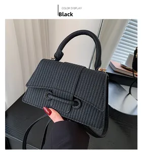 Détail d'un sac à main noir à texture tressée avec finitions dorées et poignée