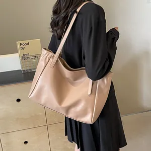 Vue latérale du grand sac cabas abricot en similicuir avec détails plissés sur modèle