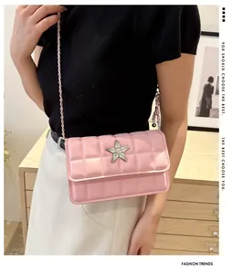 Detail of pink quilted crossbody bag featuring a rhinestone star buckle and chain strap