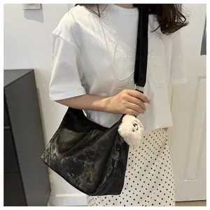 Detail of black semi-circle tote bag with mottled texture and plush dog charm