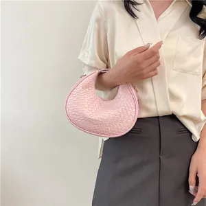 Detailed view of pink woven leather crescent bag with gold hardware on model