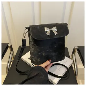 Detalle del bolso de hombro negro con lazo plateado y textura de cuero con efecto envejecido