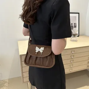 Detail der braunen Falten-Schultertasche mit silberner Schmetterlingsschnalle in Matt