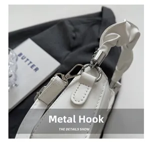Detail of silver hardware hook and pleated leather handle on a white crossbody bag