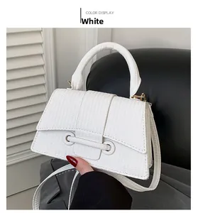 Détail d'un mini sac carré tressé blanc avec poignée incurvée et ongles rouges de mode