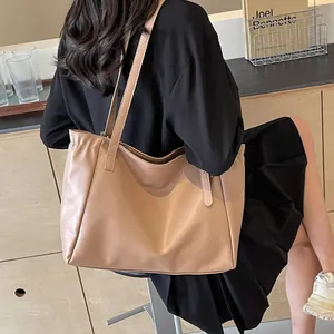 Sac fourre-tout abricot minimaliste en similicuir mat porté par un mannequin en studio