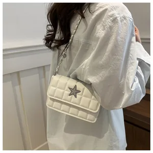 Close-up of white quilted chain bag featuring a silver star buckle with sparkling rhinestones