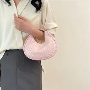 Detail of pink woven texture on a crescent hobo bag with gold zipper and metal hardware