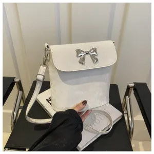 Detalle del mini bolso de cubo blanco con hebilla de lazo plateado y textura de ante suave