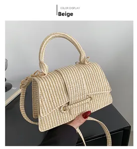 Détail d'un sac à main beige tissé avec garniture dorée et bandoulière réglable