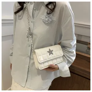 Close-up of a white quilted crossbody bag with a silver star buckle and chain strap