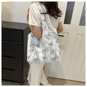 Détail du sac cabas en toile blanche avec imprimés papillons bleus et texture brute