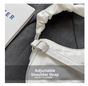 Detail of white quilted crossbody bag with adjustable ruched strap and silver buckle