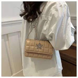 Close-up of beige quilted crossbody bag featuring a rhinestone star and chain strap