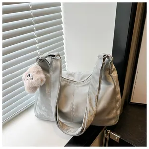 Detail of silver metallic tote bag with pink plush puppy charm and smooth zipper