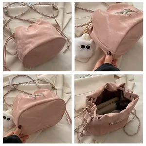 Detail of pink drawstring bucket bag with marble texture and plush monster charm
