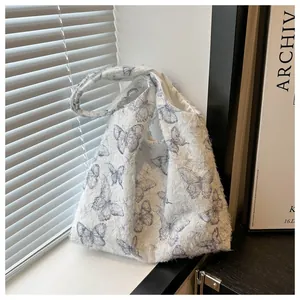 Détail du sac cabas en peluche blanche avec imprimé papillon bleu sous une lumière douce