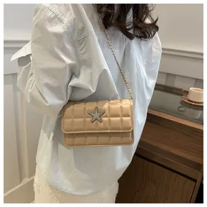 Close-up of beige quilted crossbody bag with rhinestone star and chain strap on a model