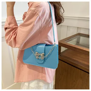 Close-up of sky blue shoulder bag with silver metal bow clasp and chunky chain detail