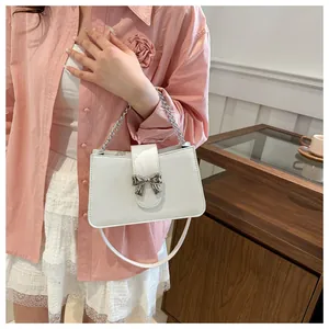 Detail of white leather shoulder bag with silver bow accent and versatile straps